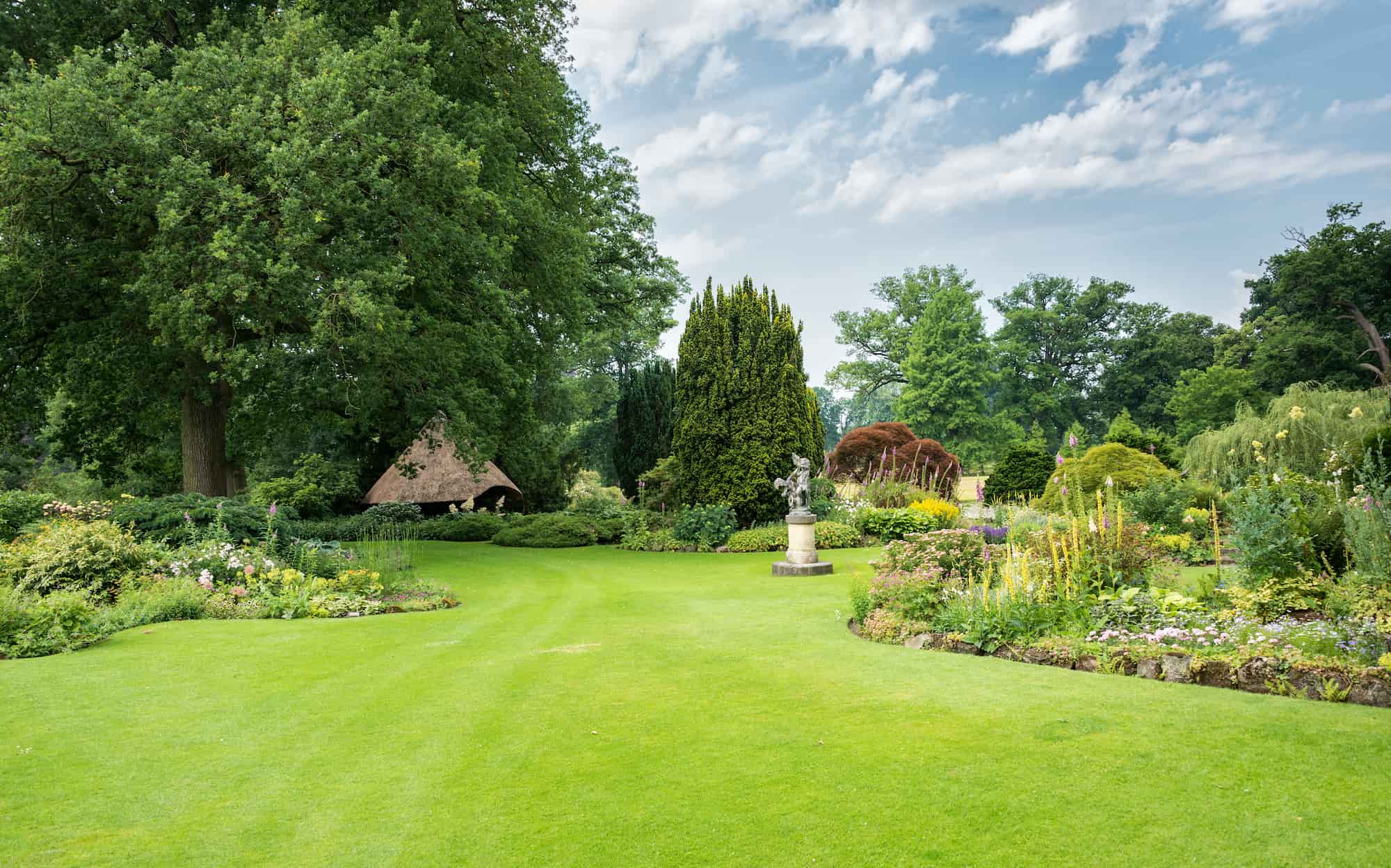 Ruime groene parktuin met gazon, bomen en beplantingszones