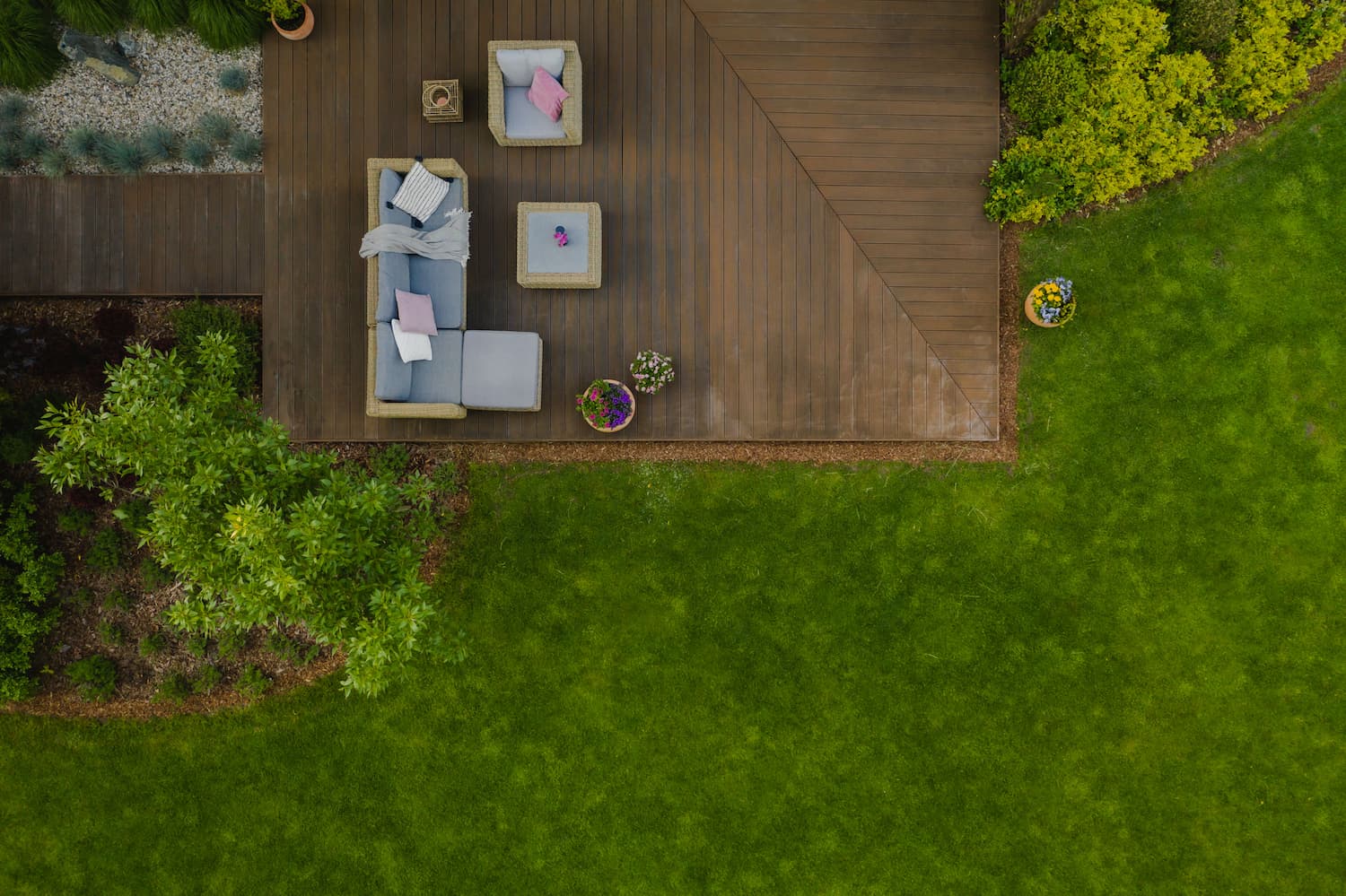 Luchtbeeld van een woning met gazon, bomen en aangelegde tuinstructuur